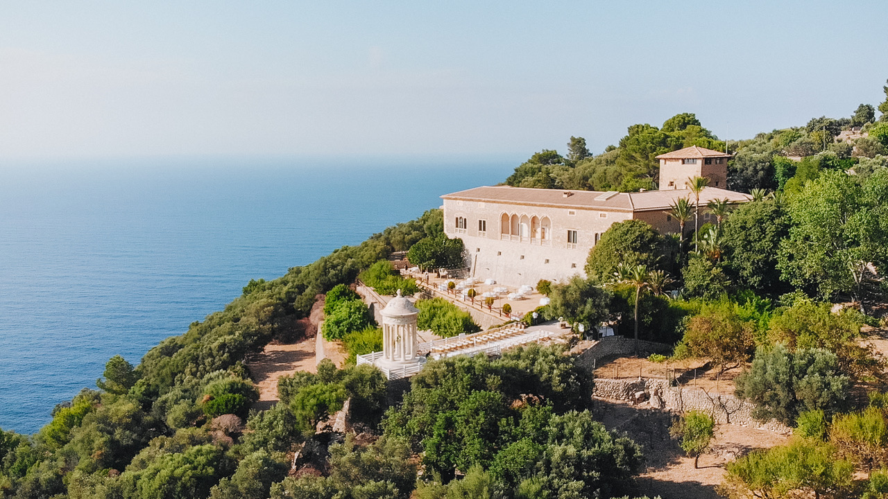 Finca histórica de piedra con galería de arcos y jardines sobre el mar